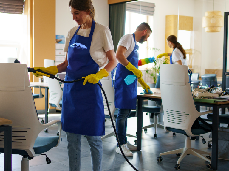 Drei Personen reinigen Büromöbel mit Sprayflaschen und Dampfreinigern.